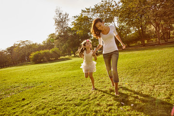Naklejka na ściany i meble Lifestyle portrait mom and daughter in happines at the outside in the meadow