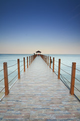 Fototapeta premium long pier heading to the sea under the beautiful blue sky.