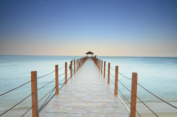 Obraz premium long pier heading to the sea under the beautiful blue sky.