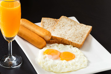 Fried eggs with sausages and bread on the white plate