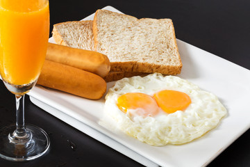 Fried eggs with sausages and bread on the white plate