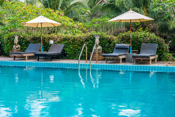 Sunbeds and parasols on deck nearby swimming pool. The luxury outdoor recreation for tourist.