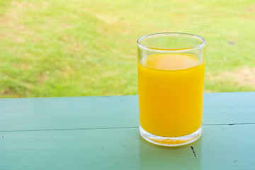 Glass of orange juice on table in backyard. It is a drink for refreshment.