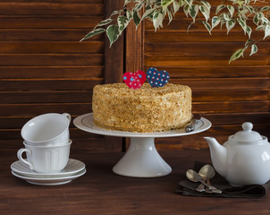 Homemade cake on a ceramic stand for the cake, tea set, paper hearts, a flower. Valentine's day romantic Breakfast. Vintage and rustic style