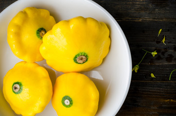 Yellow patty pan squash in the bowl on wooden background