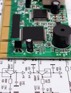 Printed circuit board lying on diagram of electronics, technology