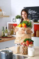 Young woman holding grocery shopping bag with vegetables 