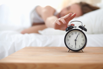 Young sleeping woman and alarm clock in bedroom at home - obrazy, fototapety, plakaty