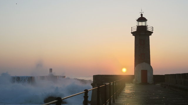 Lighthouse Felgueirasin Porto with waves and sun at sunset
