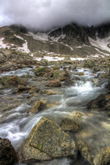 Ominous clouds above a small stream in the mountains of the Swiss Alps, HDR.