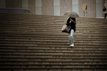 Young adult woman walks down the stairs in the rain