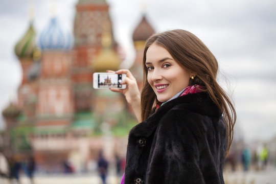 Young beautiful woman tourist taking pictures on mobile phone