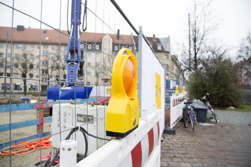 A warning light in front of a construction site with a crane in the background 