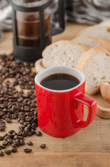Americano in red cup with coffee beans on wooden background