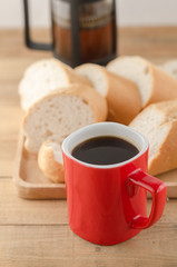 Americano in red cup with sliced bread on wooden background