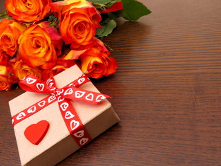 Rosenstrauch mit Geschenk auf Holzhintergrund