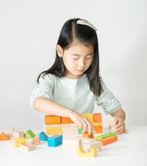 little Asian girl playing colorful wood blocks