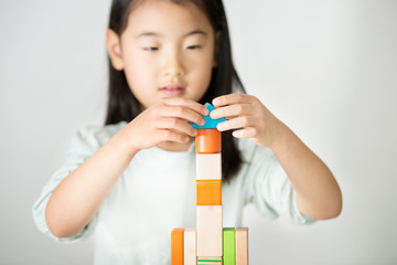 little Asian girl playing colorful wood blocks