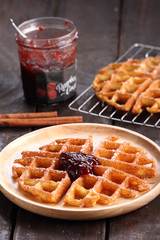 waffles with raspberry jelly on rustic wooden background
