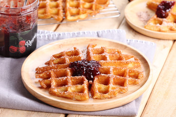 waffles with raspberry jelly on wooden background.