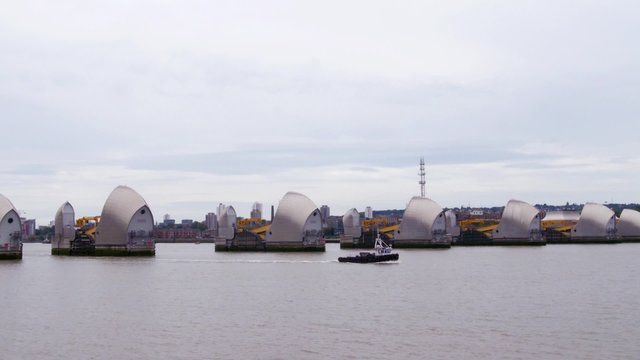 Small boat passing the river Thames barrier, London. It is a barrier to regulate the tide of the river and avoid flooding