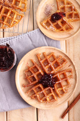 waffles with raspberry jelly on wooden background.
