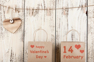 Gift cardboard bags and wooden heart on wooden background