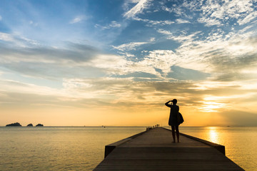 Woman standing on the pier and  sunset photographs on a tropical island. Koh Samui, Thailand