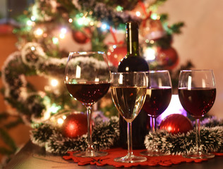 Glasses with wine in front of an illuminated Christmas tree with decorations
