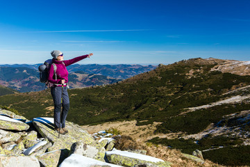 Female Hiker standing on snowy Rocks admiring scenic Winter Mountain View