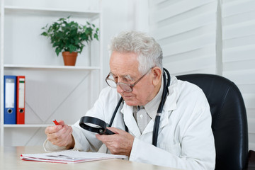 Old doctor with loupe study a  literature