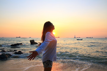 Enjoyment - free happy woman enjoying sunset. Beautiful woman in white dress embracing the golden...