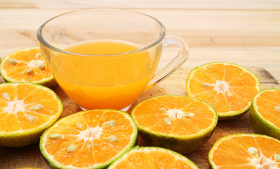 glass of fresh orange juice and oranges on a vintage wooden background