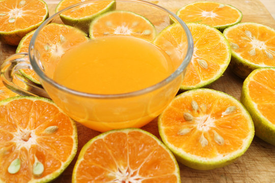 glass of fresh orange juice and oranges on a vintage wooden background