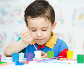 Little boy is playing with paints