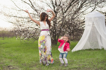 Mom and daughter dancing in nature together, the family, motherhood, entertainment, recreation, game