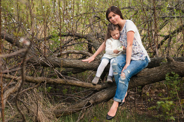 Mom kisses and hugs daughter on nature, family, motherhood, child