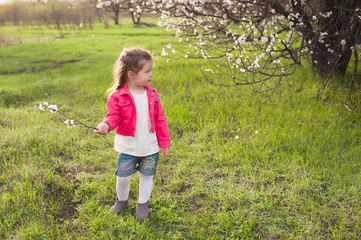 Little cute girl playing in the lush garden