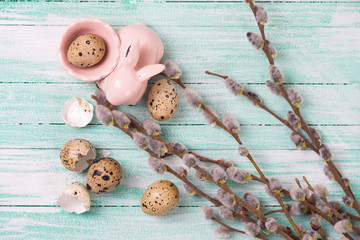 Quail eggs, Easter bunny, willow  branches on wooden background.