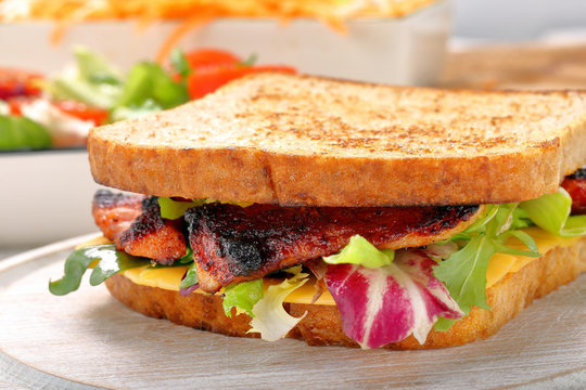 Sandwich with bacon cheese and vegetables on wooden background