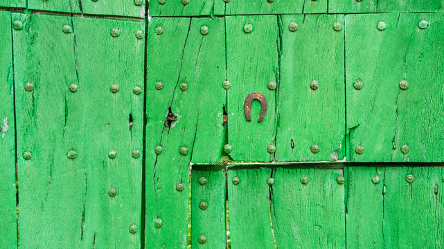 Old rusty horseshoe on green wooden door -  outdorrs