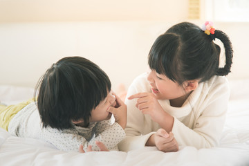 asian children lying on white bed