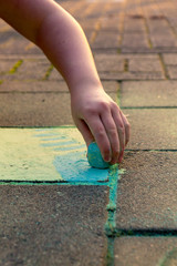 Kid playing with colored chalk on the sidewalk.
Nice colors in the golden hour. Close up of arm and hand.