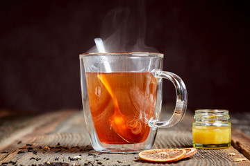 Steaming tea and honey on a wooden table