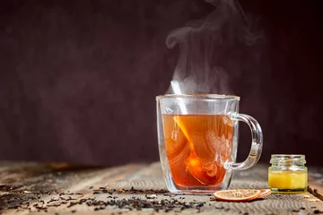 Abwaschbare Fototapete Tee Dampfender Tee und Honig auf einem Holztisch
