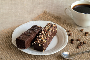 Dessert.  Two chocolate cakes on a white plate and a cup of coffee on burlap.
 