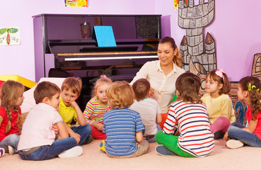 Group of kids sit and listen to teacher tell story