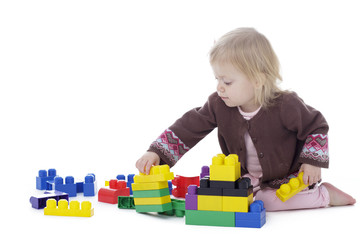 toddler girl playing with colored building blocks, holding in hands, isolated on white background