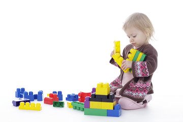 toddler girl playing with colored building blocks, holding in hands, isolated on white background