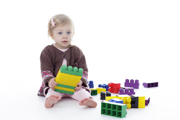 toddler girl playing with colored building blocks, holding in hands, isolated on white background